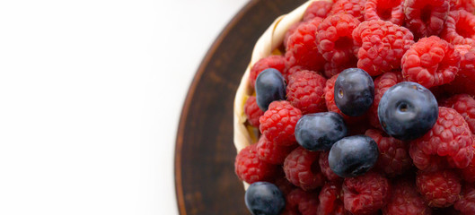 Raspberries and blueberries on the background of pottery. Black and red berries.