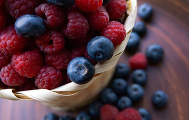 Raspberries and blueberries on the background of pottery. Black and red berries.