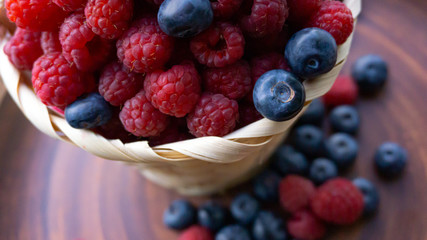 Raspberries and blueberries on the background of pottery. Black and red berries.