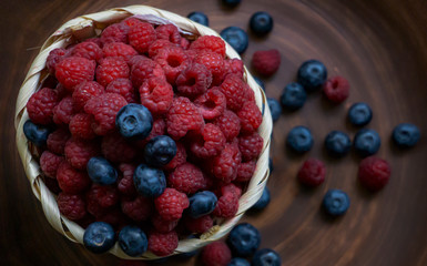 Raspberries and blueberries on the background of pottery. Black and red berries.