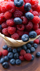 Raspberries and blueberries on the background of pottery. Black and red berries.