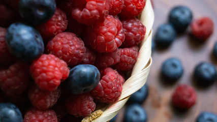 Raspberries and blueberries on the background of pottery. Black and red berries.