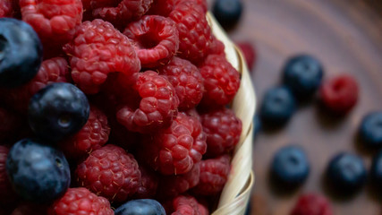 Raspberries and blueberries on the background of pottery. Black and red berries.