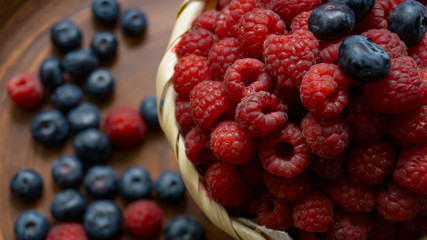 Raspberries and blueberries on the background of pottery. Black and red berries.