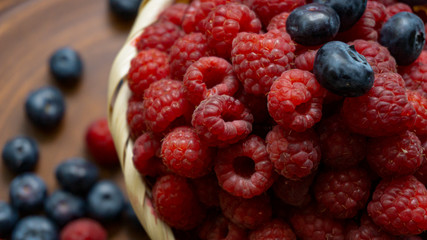 Raspberries and blueberries on the background of pottery. Black and red berries.