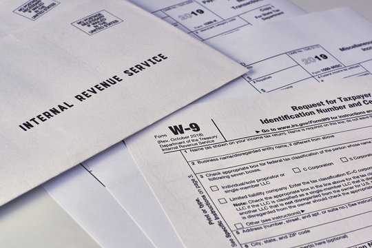 Three mails from the Internal Revenue Service lie on tax Form w-9, 1099-misc, 1099-k on a white background
