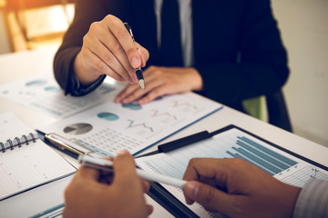 Naklejka premium Two business partnership coworkers analysis cost work progress and gesturing with discussing a financial planning graph and company financial during a budget meeting in office room.