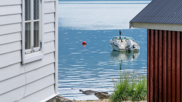 Street view in Solvorn, a cute small resort village pressed between mountains on the western shore of the Lustrafjorden. Boat in the backyard, which appears to be a sea. Midsummer day in Norway.