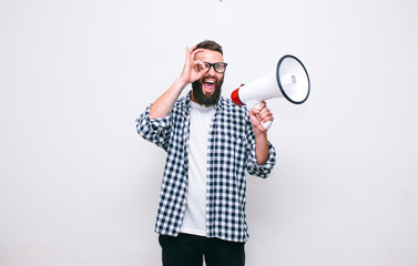 Fashion portrait of emotional hipster man with megaphone on white background in stylish sunglasses....