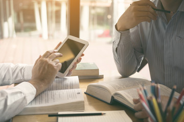 Students use the tablet to search for students' homework for their friends in the library at the university.