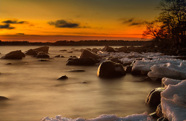 Moody picture of rocks and ice at a shore during winter