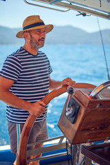 Obraz premium Sailor using wheel to steer rudder on a sailing boat.