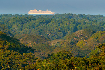 Green tropic jungle forest with big cruise chip on the sea. Exotic landscape  in Carara NP in Costa Rica. Big boat in the water, sail voyage along the ocean cast. Travelling in Cantral America.