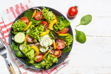 Fresh vegetables salad on white wooden table.