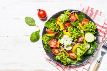 Fresh vegetables salad on white wooden table.