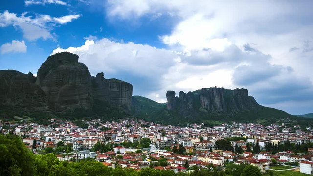 View of Meteora rocks and Kalambaka and Kastraki village at daytime in sunshine and great clouds fly over - timelapse