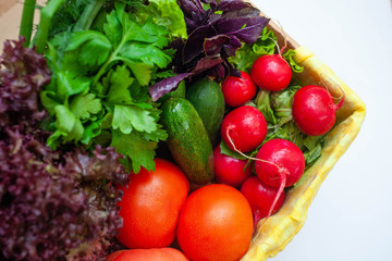 cucumbers, tomatoes, radishes, lettuce, basil, parsley in a box with a yellow napkin. space for text