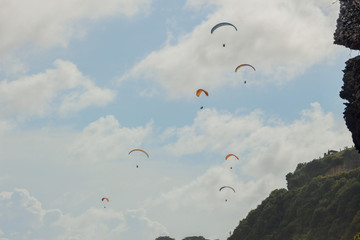 Paragliding in a blue sky in Bali, Indonesia. Paraglider tandem flying over the sea with blue water...