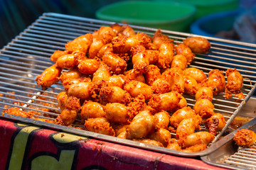 Grilled sausages (pork and rice sausage or Isaan sausage) in street food market. Picture with grain and color from film simulation filter. 