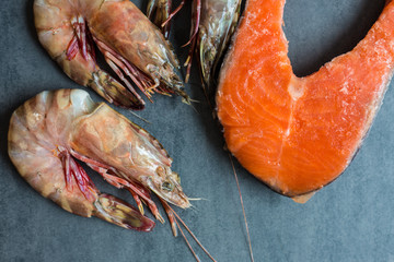 Fresh salmon fish with sea prawn shrimp on black plate, Seafood
