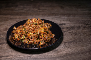 Spicy duck minced salad on wood table. Thai local food recipe Larb Ped delicious menu.