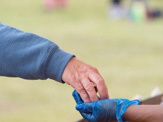 A customer hand places money in a blue hygiene gloved hand of a food seller - Image