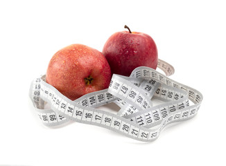 Red apple and measuring tape isolated on white background. Concept of proper diet and healthy lifestyle. White measuring tape with red apple closeup.