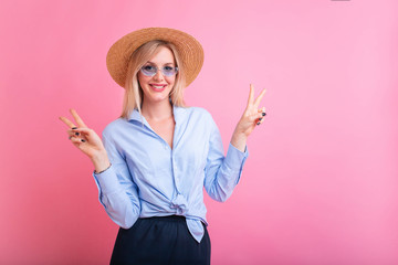 Portrait of gorgeous blond woman 30s in stylish outfit smiling and looking at camera isolated over pink background. V sign gesture, copy space