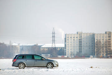 Car parked in snowy field on winter day.
