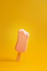 pink ice cream popsicle on yellow background bitten off a piece