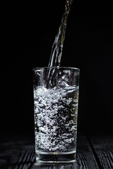 water pours into a glass on a black background