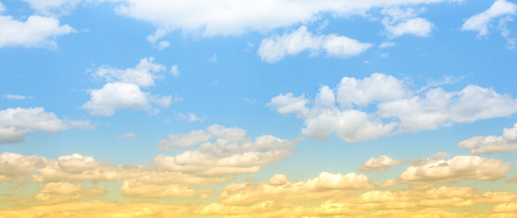 A cloudy blue sky with fluffy clouds and a yellowish sunset style
