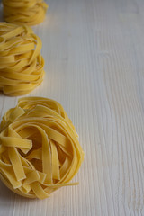Top view of fettuccine pasta on white wooden table background in vertical with copy space