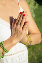Young yoga teacher touching her hands in front of chest practising yoga outside in park