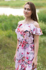 Fototapeta premium The young woman in a dress poses in the village