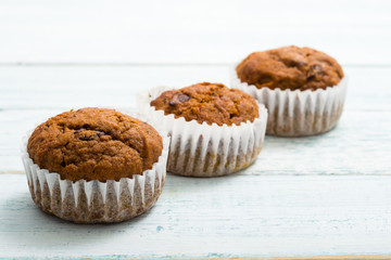 three chocolate muffins at paper cup, old white wooden table