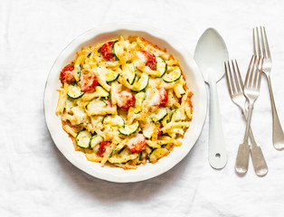 Roasted zucchini and cherry tomatoes baked mac and cheese  on the light background, top view. Vegetarian healthy lunch