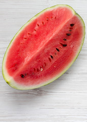 Fototapeta na wymiar Fresh cut watermelon on a white wooden background, overhead view. Flat lay, from above, top view.