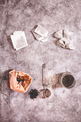Metal thermos and tea infuser. Black tea in a jar and a paper bag. Zero waste plastic free kitchen on gray  background. concept sustainable lifestyle or Recycling and ecology