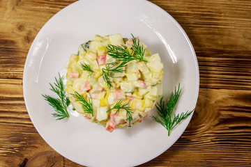 Salad with crab sticks, sweet corn, cucumber, eggs and mayonnaise on wooden table. Top view