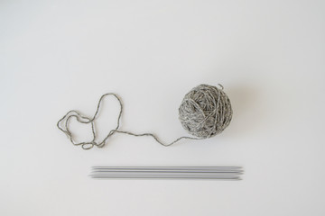 Ball of grey wool yarn and hosiery iron spokes on white background
