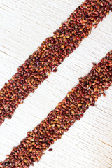 Grains of red millet lined with two stripes on a white background. Close-up
