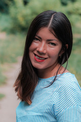 Smiling teen brunette girl outside with a natural green of background