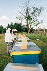 Look at a apiary and two apiarist working with bees