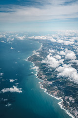 Flight over the coast of Portugal Lissabon region . Aerial view through the airplane window with clouds water and coastline.