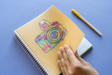 Female hand opens notebook, and a pen on the purple background. Ready for studying photography
