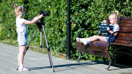 Children with photo appart in a city park Two girls on street make a video for the Internet, record a video blog for the camera.