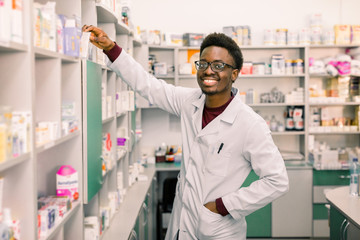 African-american man pharmacist on his workplace in modern drugstore. Health care medical...