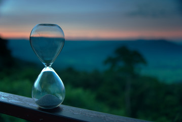 An hourglass with blur forest in twilight time at a morning