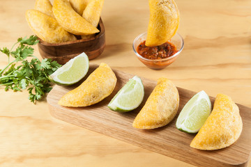 tasty food colombian, empanada with spicy sauce; photo on wooden background.